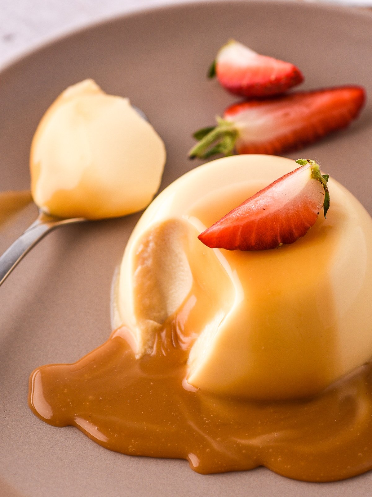 Image shows a Baileys Panna Cotta drizzled with chocolate caramel sauce and topped with fresh strawberries.