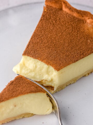 The perfect slice of milktart shown on a plate with a fork through it. You can see the cream texture of this South African Dessert.