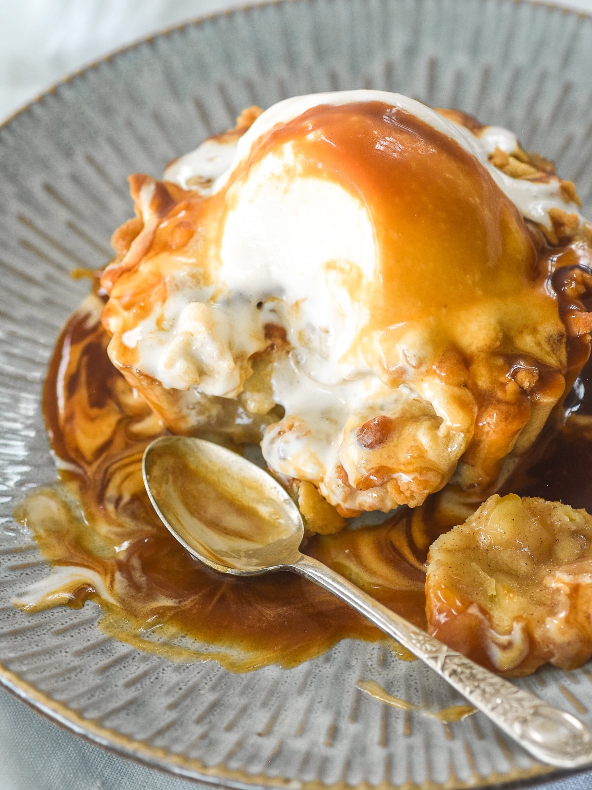 Image shows the tartlet with ice cream and caramel sauce poured over it. A spoon is shown next to a missing bite.