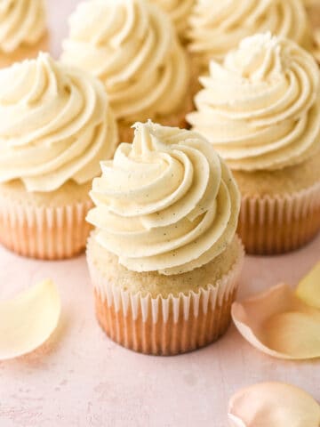 Vanilla bean cupcakes shown on a pink kitchen counter.