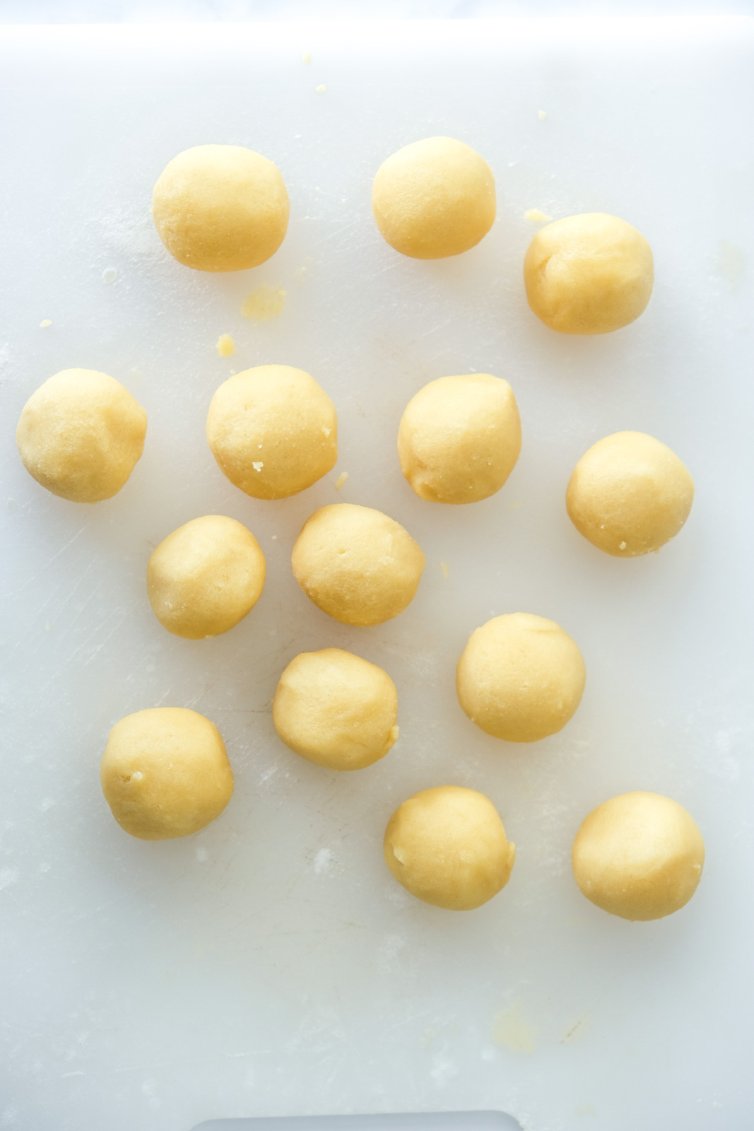 Image shows step 6 of how to make Nutella thumbprint cookies: rolling the dough into balls.