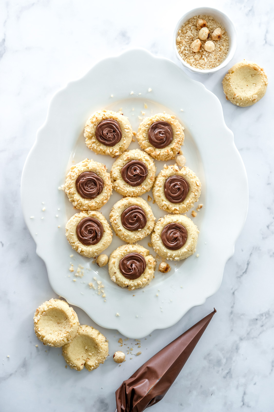 Image shows the filled Nutella thumbprint cookies on a serving plate.