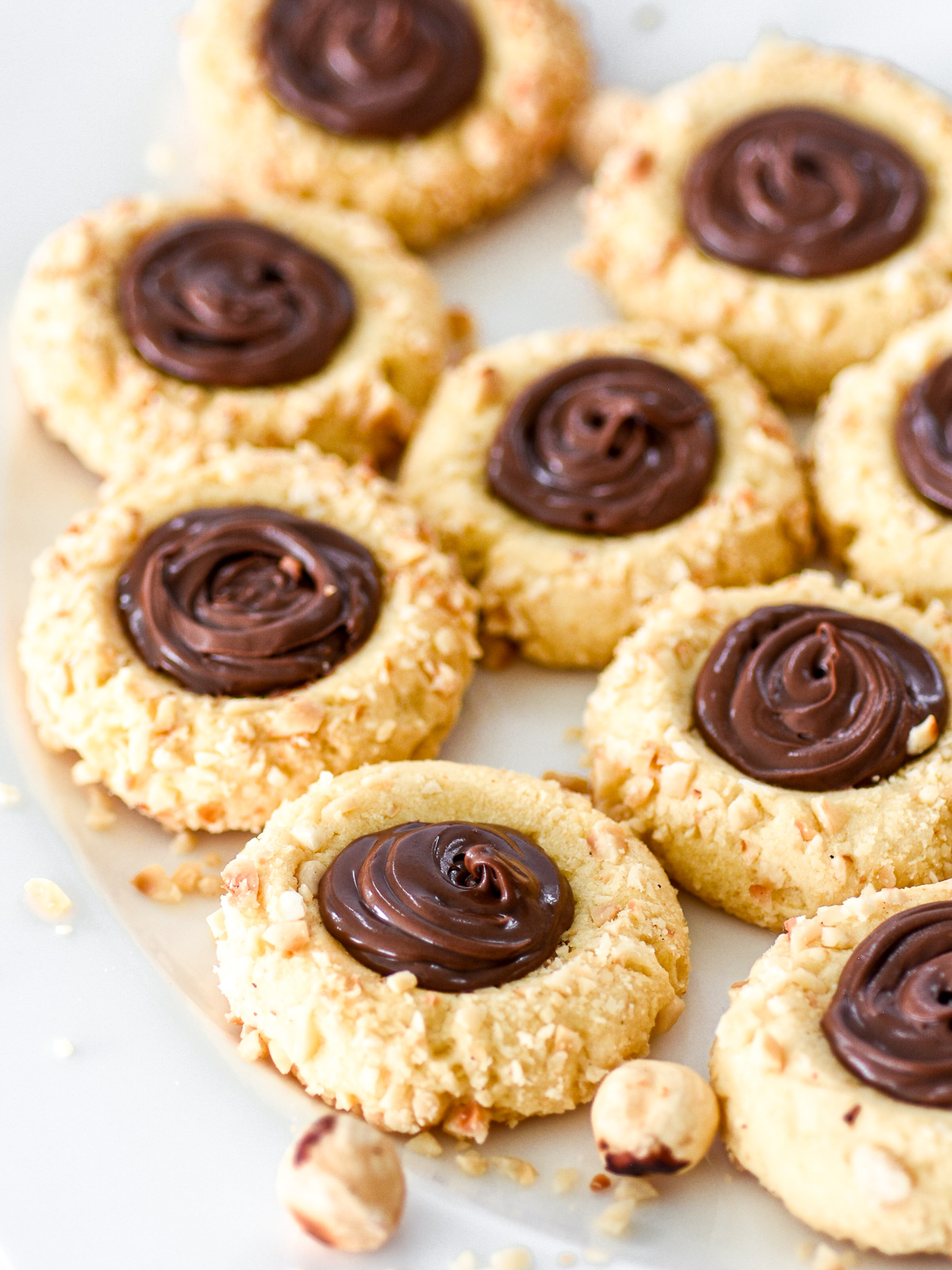 Nutella Thumbprint Cookies shown on a white plate, you can see the swirls of Nutella in the center of the cookies.