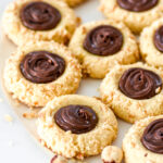 Nutella Thumbprint Cookies covered in crushed hazelnuts shown on a white plate.