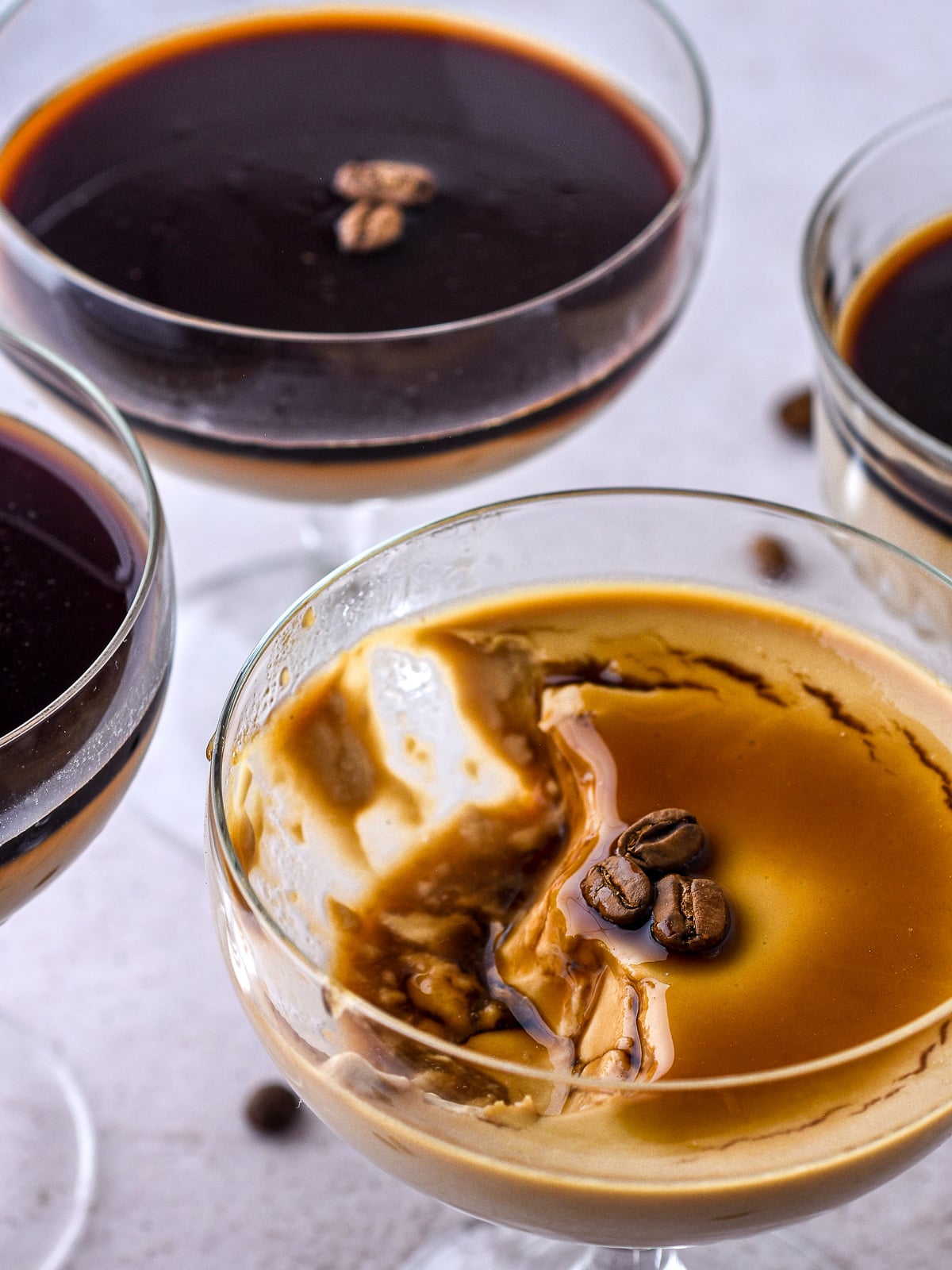 Espresso Panna Cottas shown from above, the one panna cotta has a spoonful of the dessert missing.
