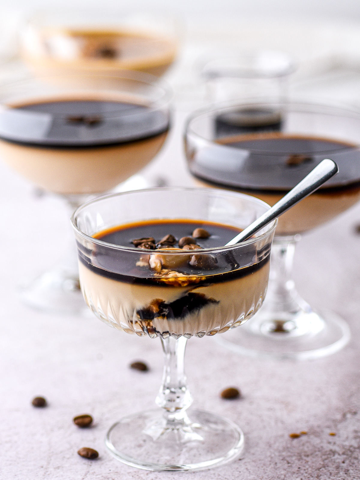 Image shows different dessert glasses filled with espresso panna cotta topped with espresso syrup.