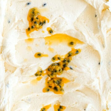 Passion fruit buttercream shown up close and swirled. It has been drizzled with extra passionfruit pulp.