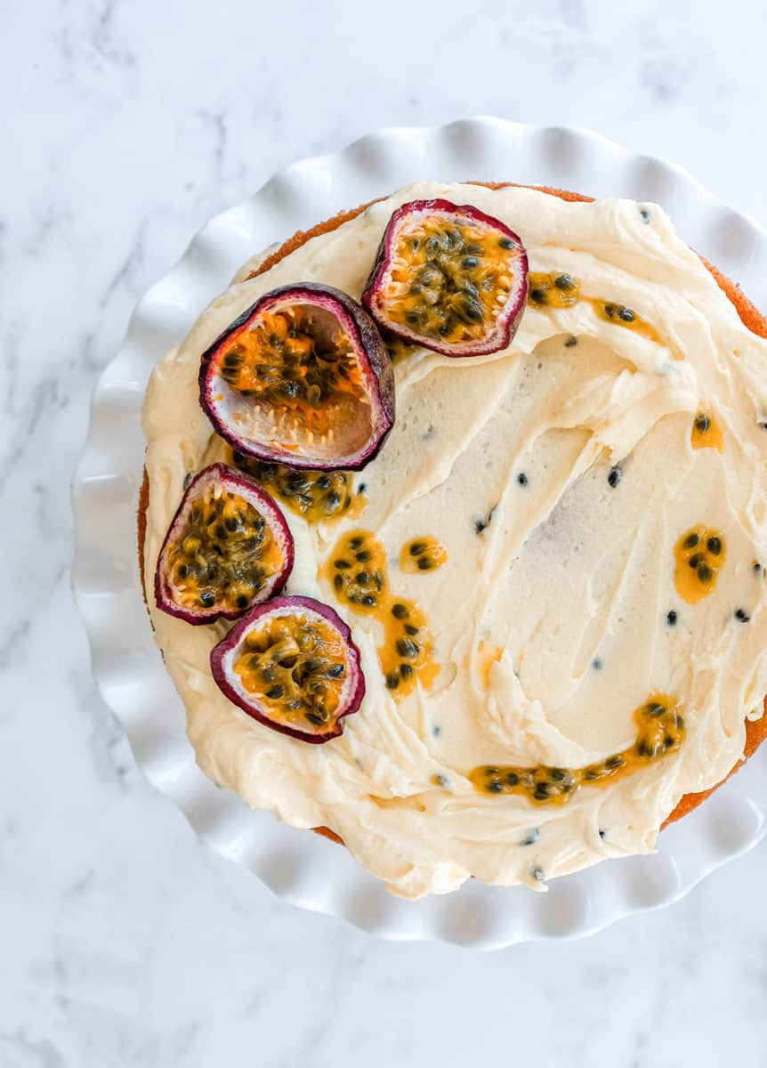 Image showing the Passion Fruit Buttercream swirled over a cake. Fresh passionfruit halves have been placed on top of the cake.