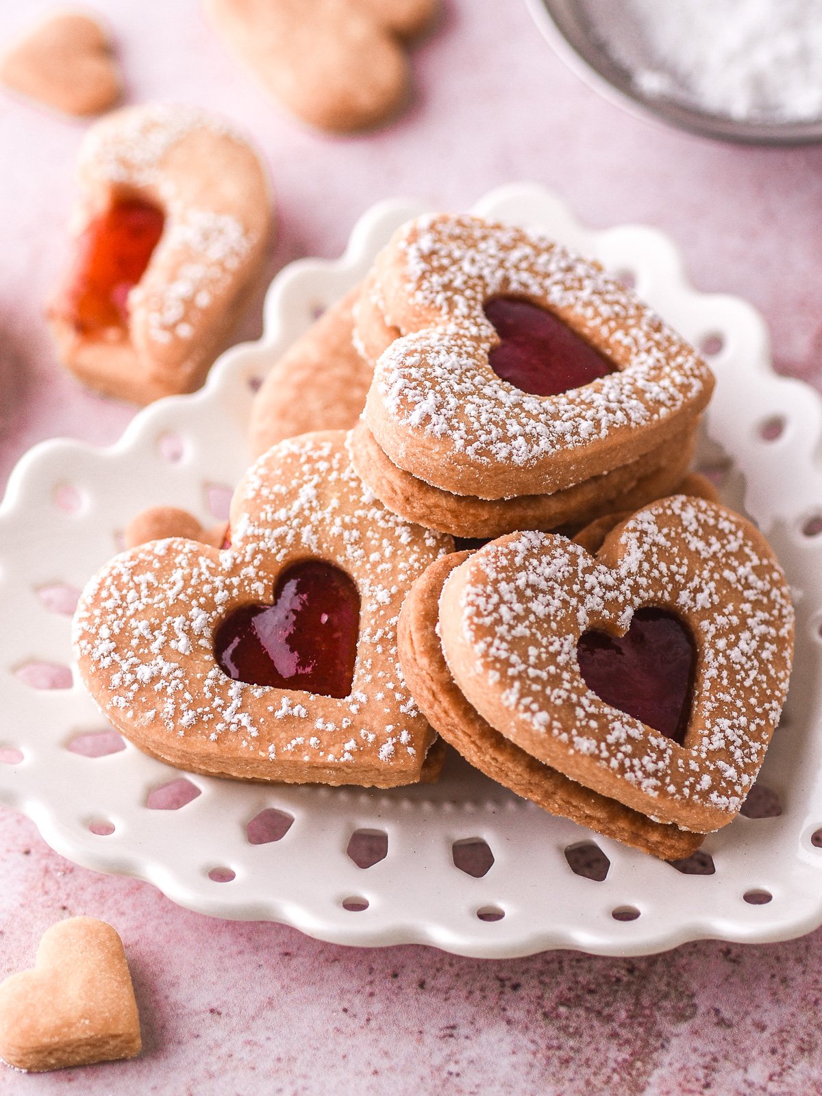 Image showing heart shaped jam sandwich cookies filled with jam on a white plate.