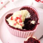 Red Velvet Mug Cake shown baked in a heart shaped ramekin, a spoonful is missing.