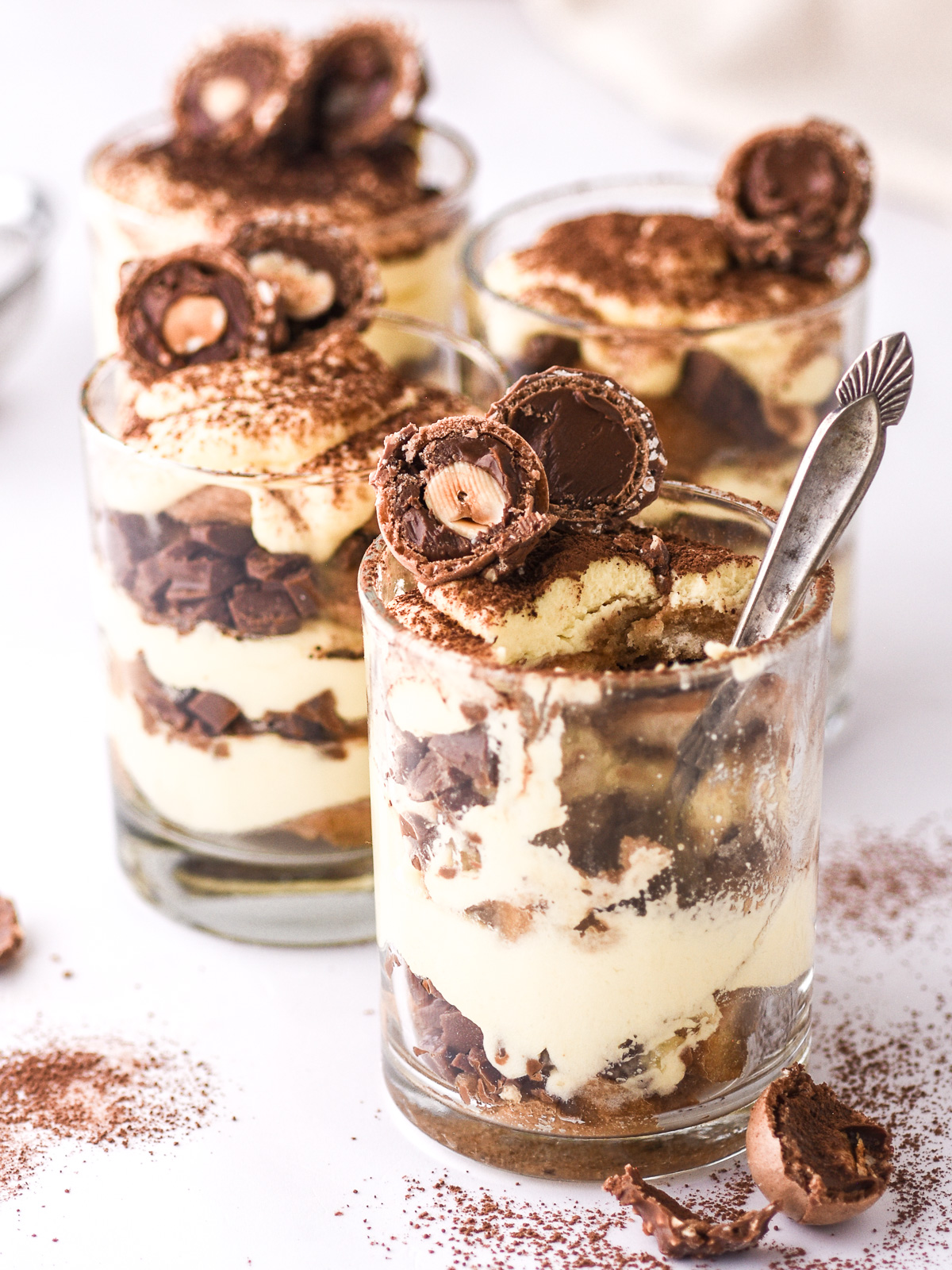 image showing 4 glasses filled with the tiramisu dessert and decorated with Ferrero Rocher chocolates.