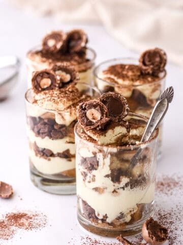 Mini Tiramisu Cups shown on a marble kitchen counter, the cup in the front has a spoonful missing.