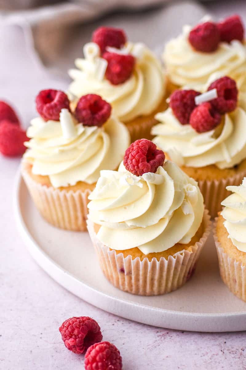 Raspberry and White Chocolate Cupcakes shown on a white plate on a kitchen counter.