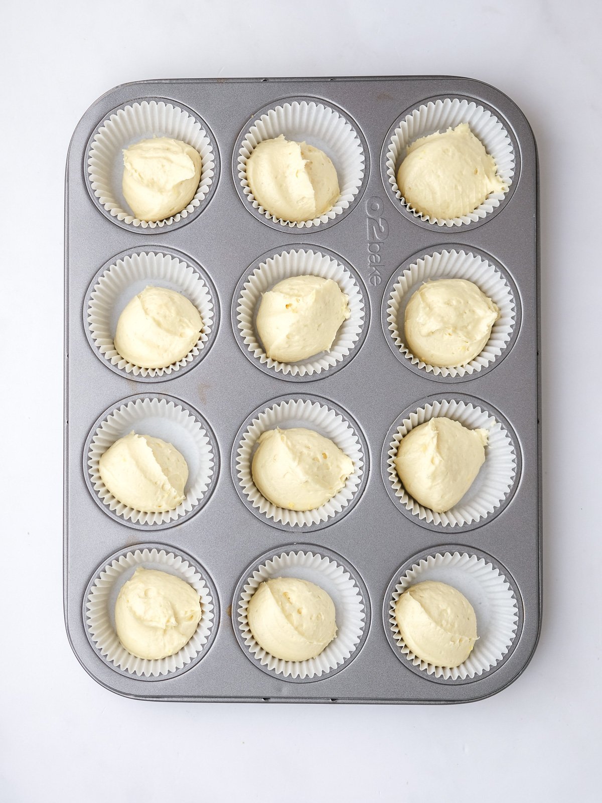 Image shows step 5 of how to make lemon drizzle cupcakes.