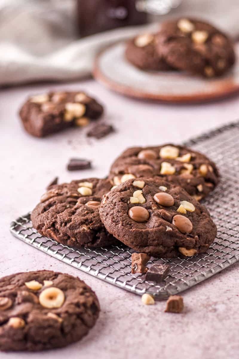 Hazelnut and Chocolate Cookies shown on a kitchen counter. Some cookies are on a wire cookie cooling rack. 