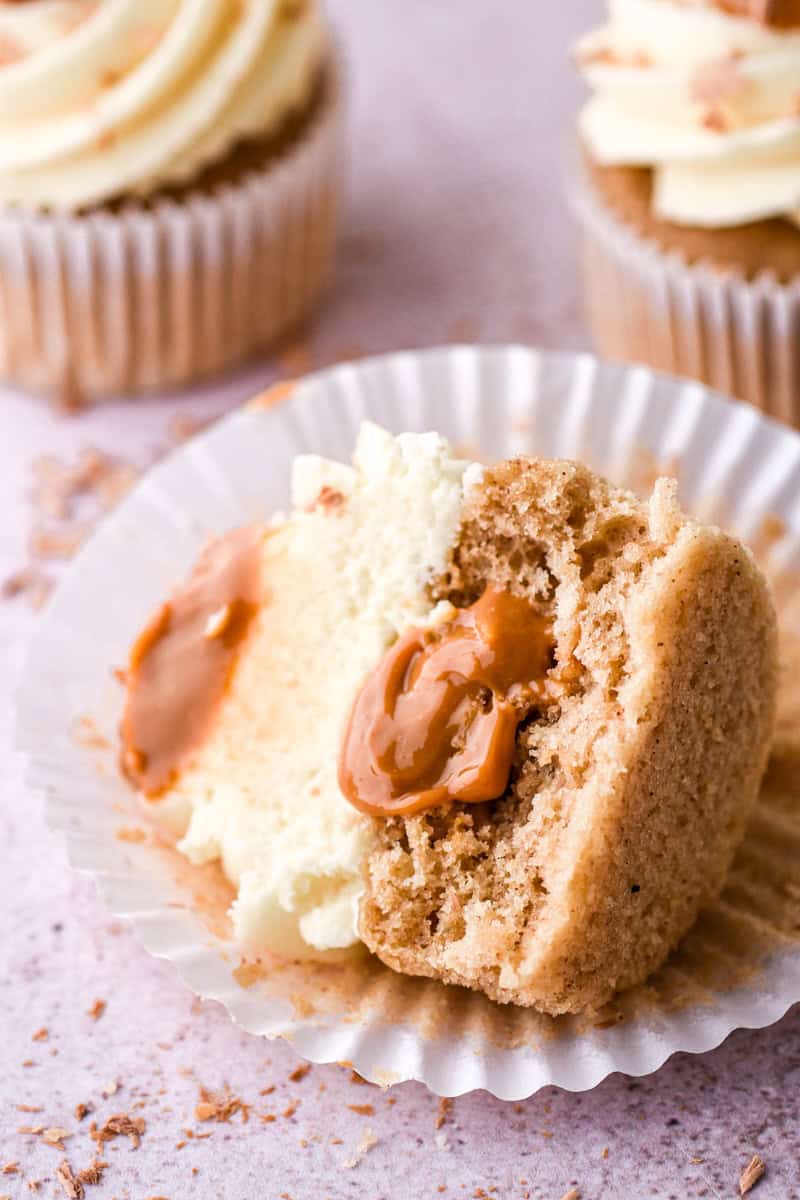 Banoffee Cupcake shown lying on its side in the cupcake paper, it is cut in half so that you can see the dulce de leche filling.