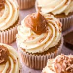 Banoffee cupcakes shown on a kitchen counter. You can see the big swirl of caramel on the cupcakes that has been decorated with chocolate shavings.