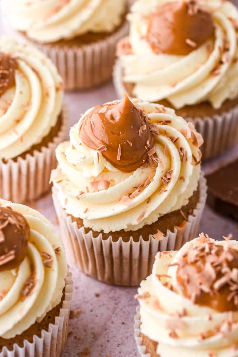 Banoffee Cupcakes photographed up close so you can see the swirl of vanilla frosting, the dollop pf dulce de leche and the chocolate shavings.