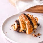 Puff pastry Nutella Croissant shown on a white plate on a kitchen counter.