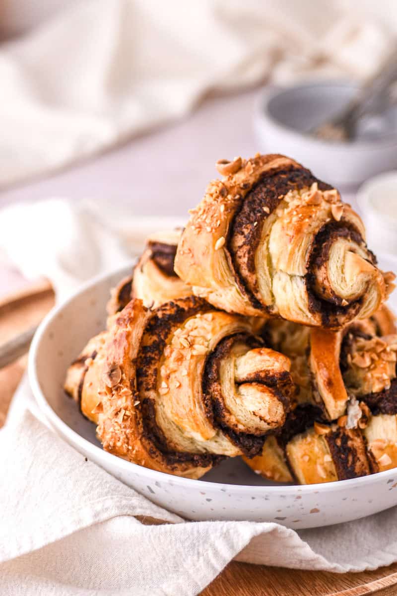 Nutella Croissants shown piled up in a bowl on top of a linen napkin.
