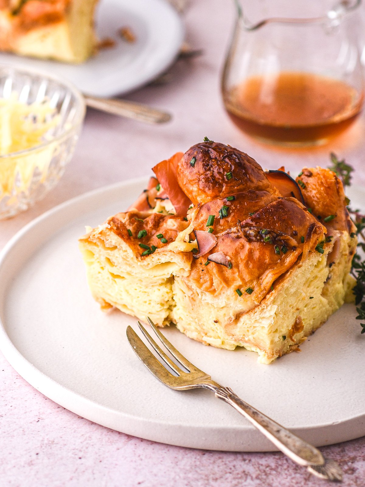A slice of the ham and cheese croissant bake shown on a plate next to a fork.