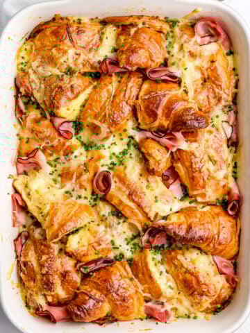 Ham and cheese croissant bake shwon in a white casserole dish from above.