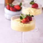 Vanilla Bean Custard shown in a tall stemmed dessert glass with fresh strawberries.