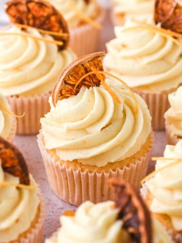 Image showing decorated orange cupcakes on a kitchen counter.