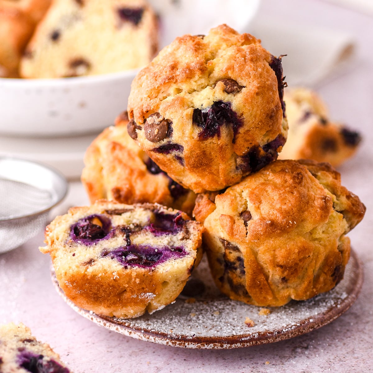 Blueberry and chocolate chip muffins shown piled high on a small side plate.