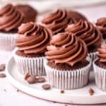 Chocolate Fudge Cupcakes shown on a white plate on a kitchen counter.