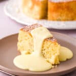 Image shows a slice of cake on a beige coloured plate drizzled with custard.