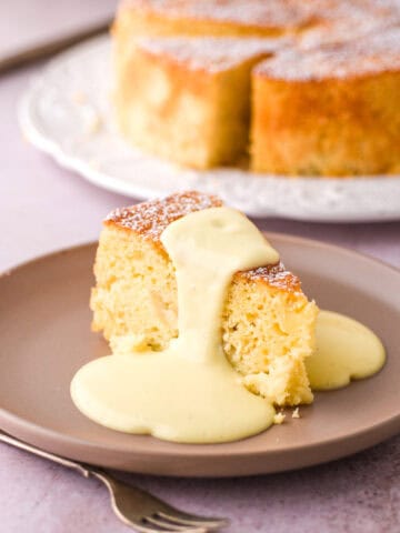 Image shows a slice of cake on a beige coloured plate drizzled with custard.