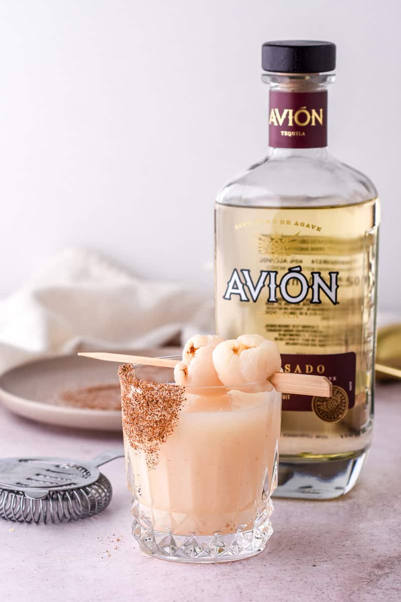 The cocktail is shown in a short cut glass tumbler in front of a bottle of tequlia.