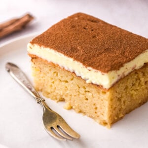 Image shows a slice of milktart malva pudding, you can see the moist malva and the creamy milktart layer.