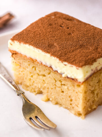 Image shows a slice of milktart malva pudding, you can see the moist malva and the creamy milktart layer.