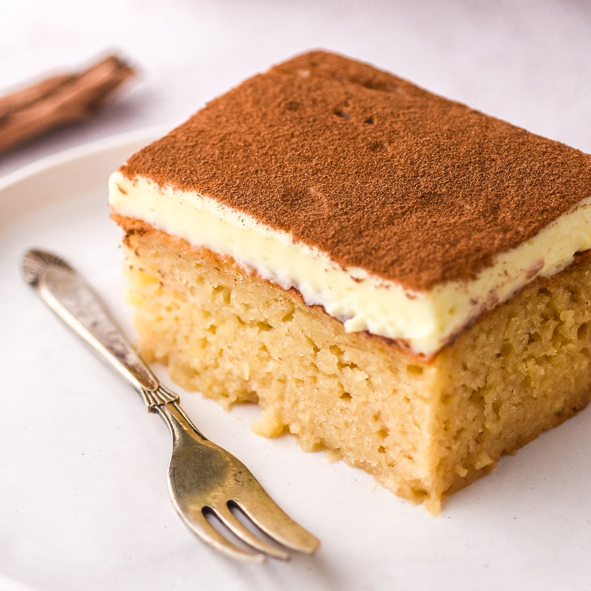 Image shows a slice of milktart malva pudding, you can see the moist malva and the creamy milktart layer.