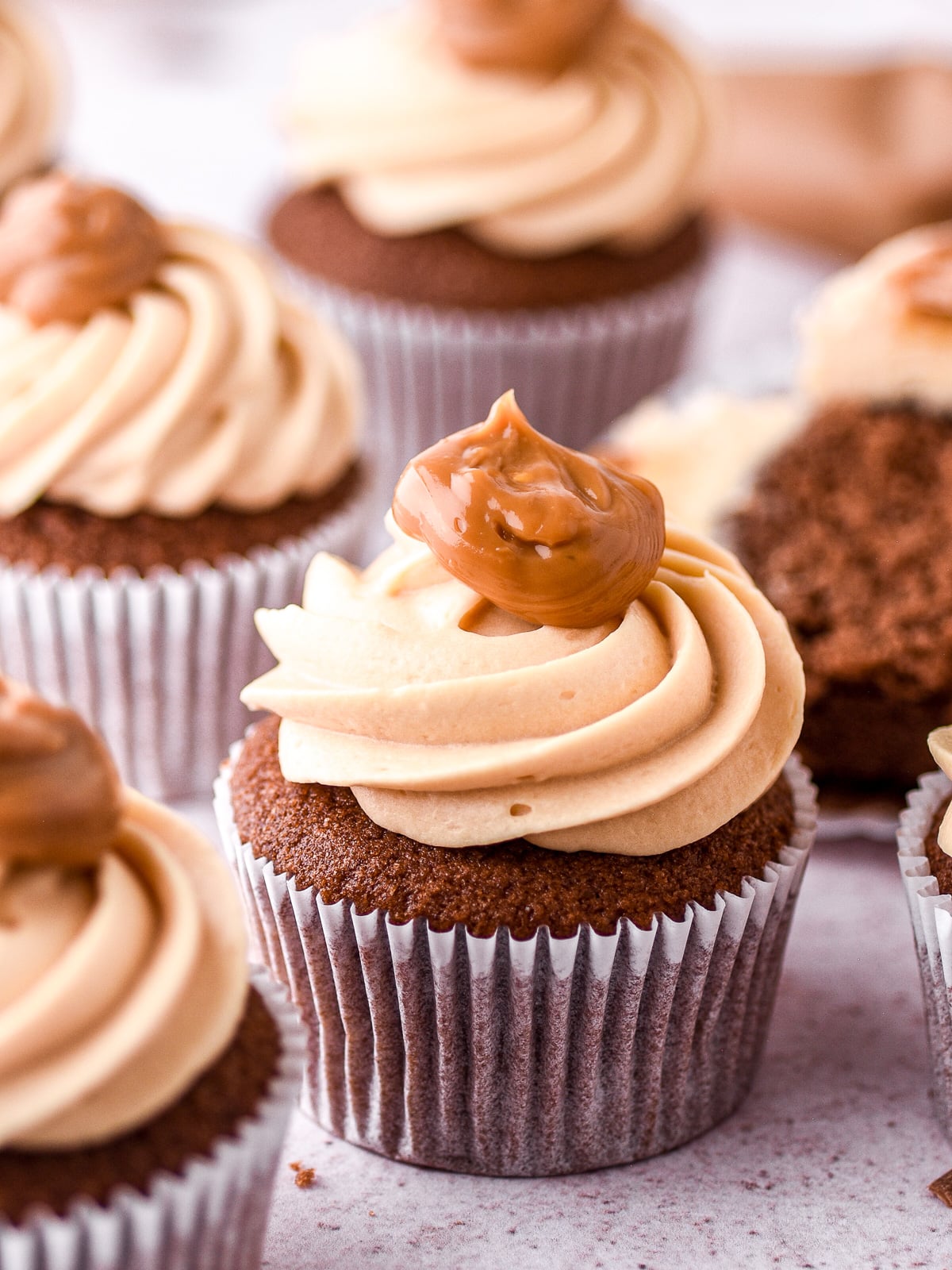 Caramel dulce de leche cupcake shown up close, you can see the perfect swirl of caramel frosting and the dollop of dulce de leche sitting on top of the frosting.