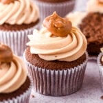 Dulce de leche chocolate cupcake shown on a kitchen counter with more cupcakes in the background.