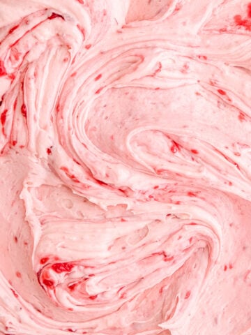Close up image of the frosting swirled, you can see the smooth texture and the raspberry seeds.