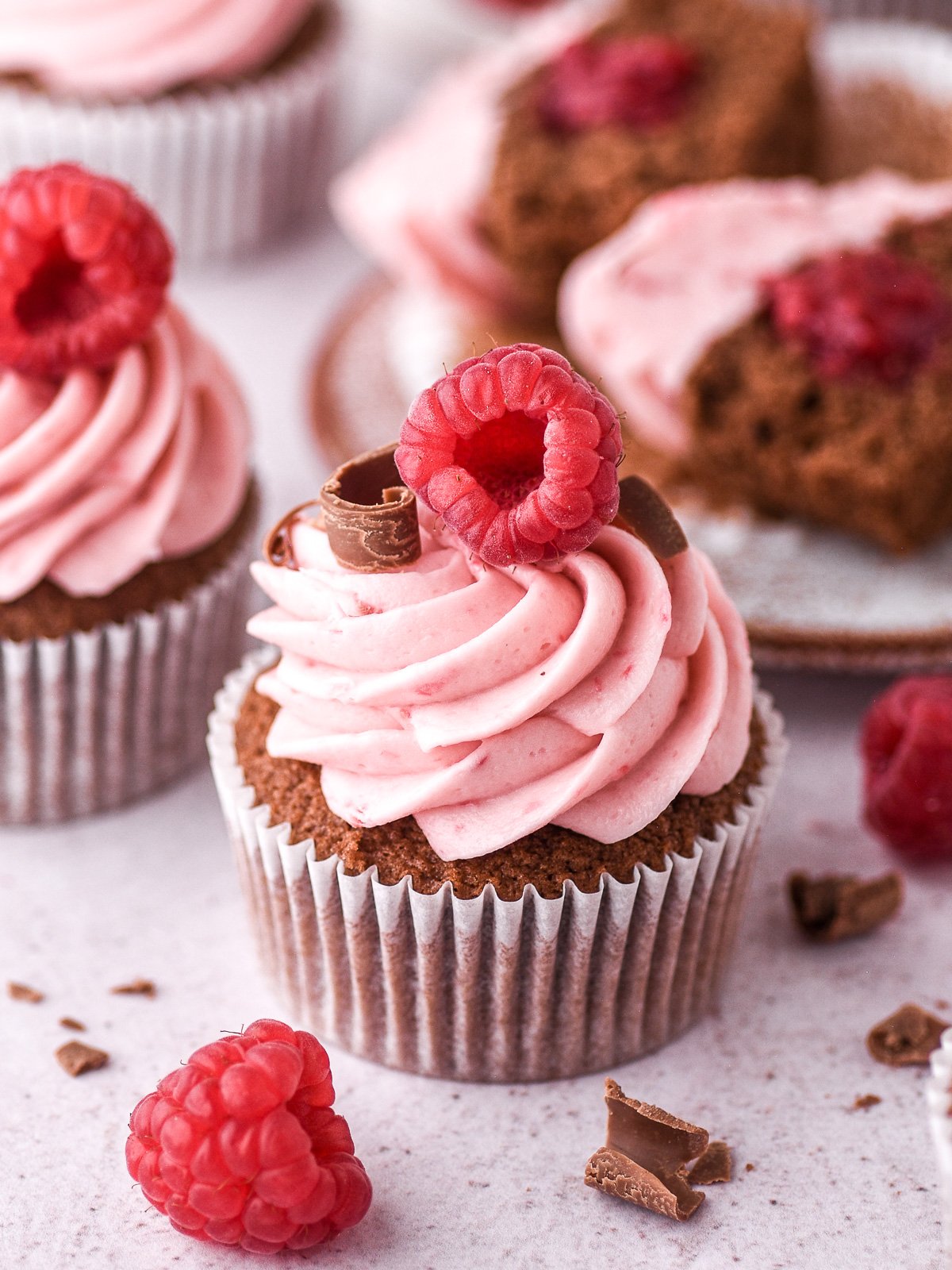 Decorated chocolate and raspberry cupcake shown in front of other cupcakes. 