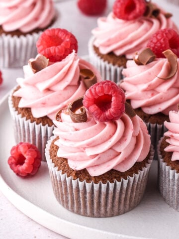 Raspberry Chocolate Cupcakes decorated with curls of chocolate shown on a white plate.