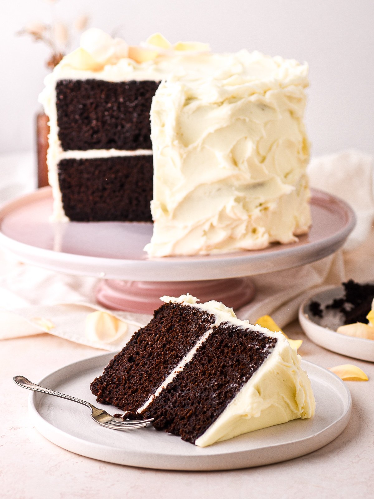 Image shows a slice of cake in the foreground and the whole cake in the background.