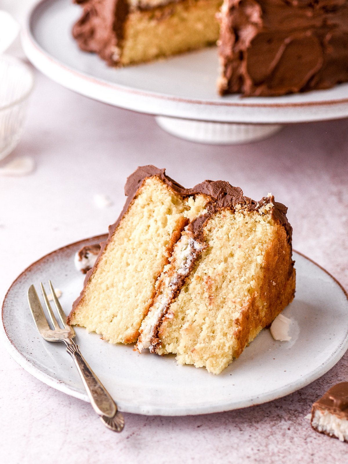 A slice of Bounty Cake on a white plate next to a fork.