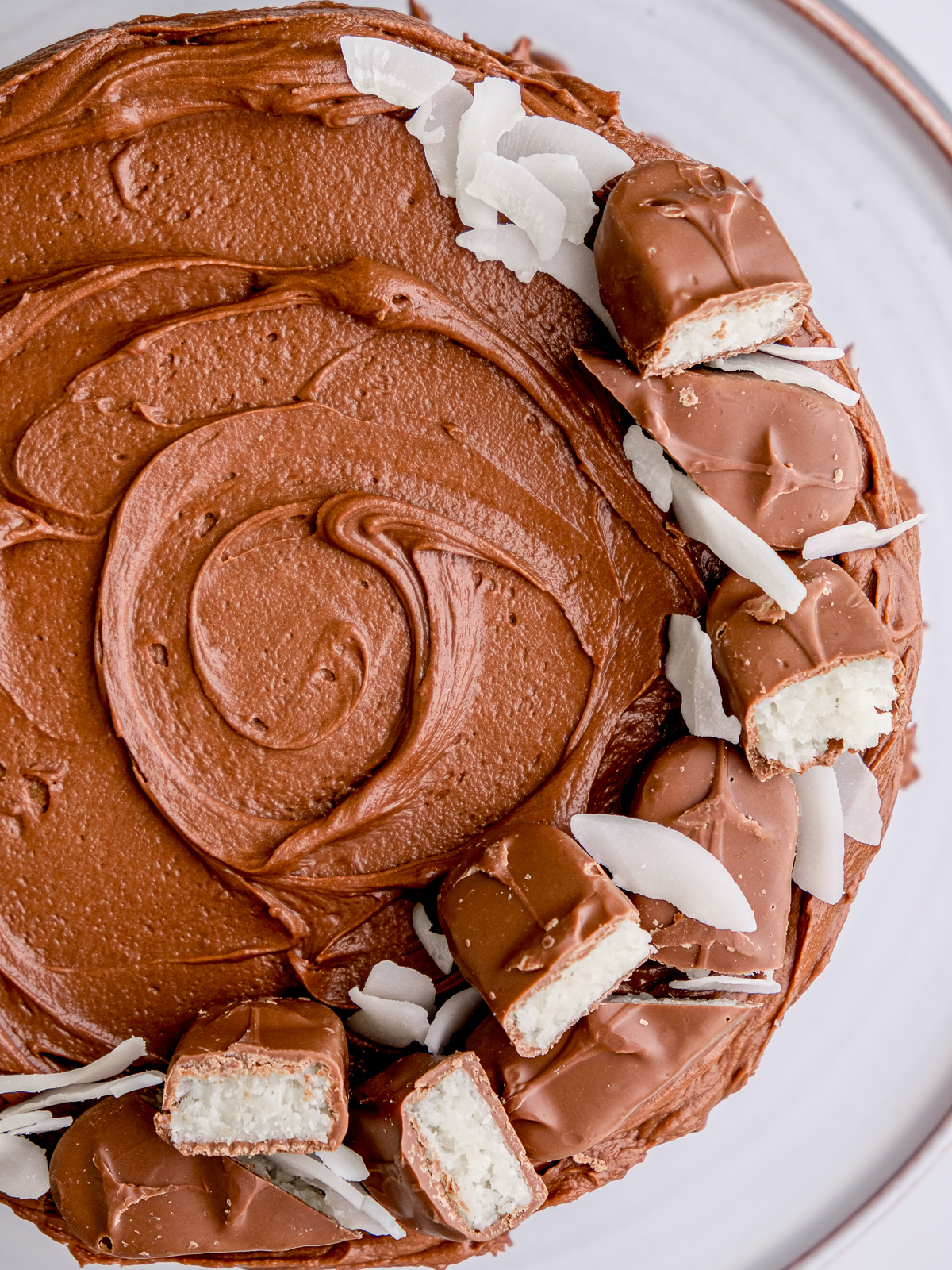 image showing Bounty chocolate coconut cake from above, you can see the swirled melted chocolate frosting.