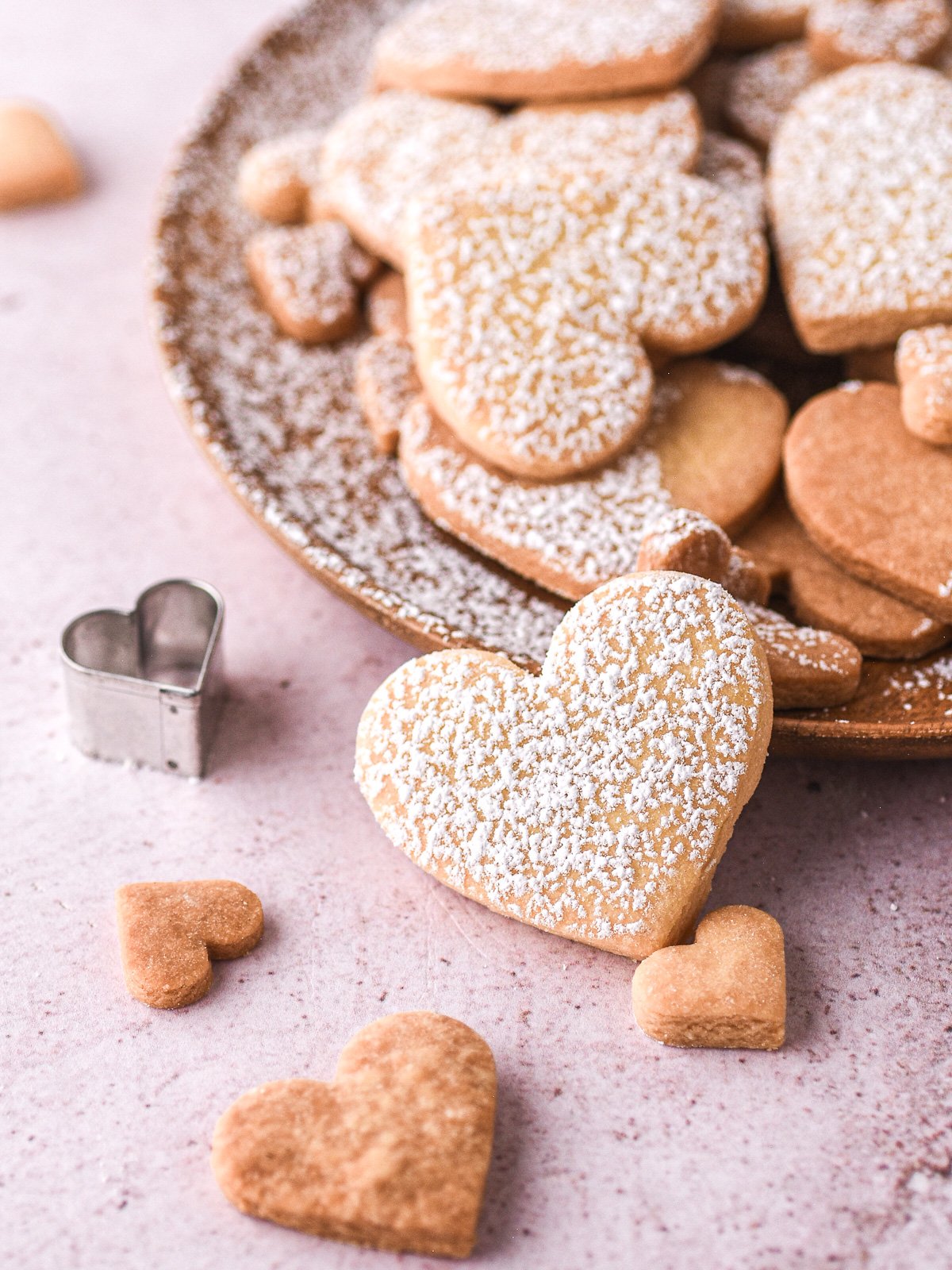 Image shows close up of a cookie that has fallen off a plate filled with cookies.