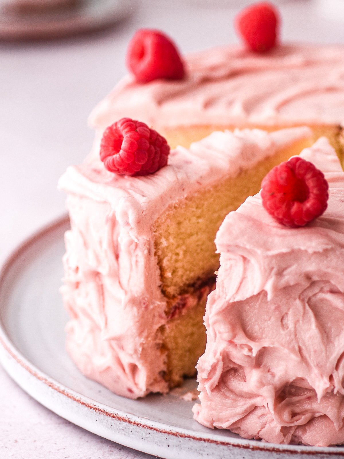 Image showing a pink raspberry and vanilla cake with some slices cut.