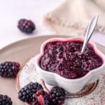 Image showing the compote in a small fluted bowl next to fresh berries.
