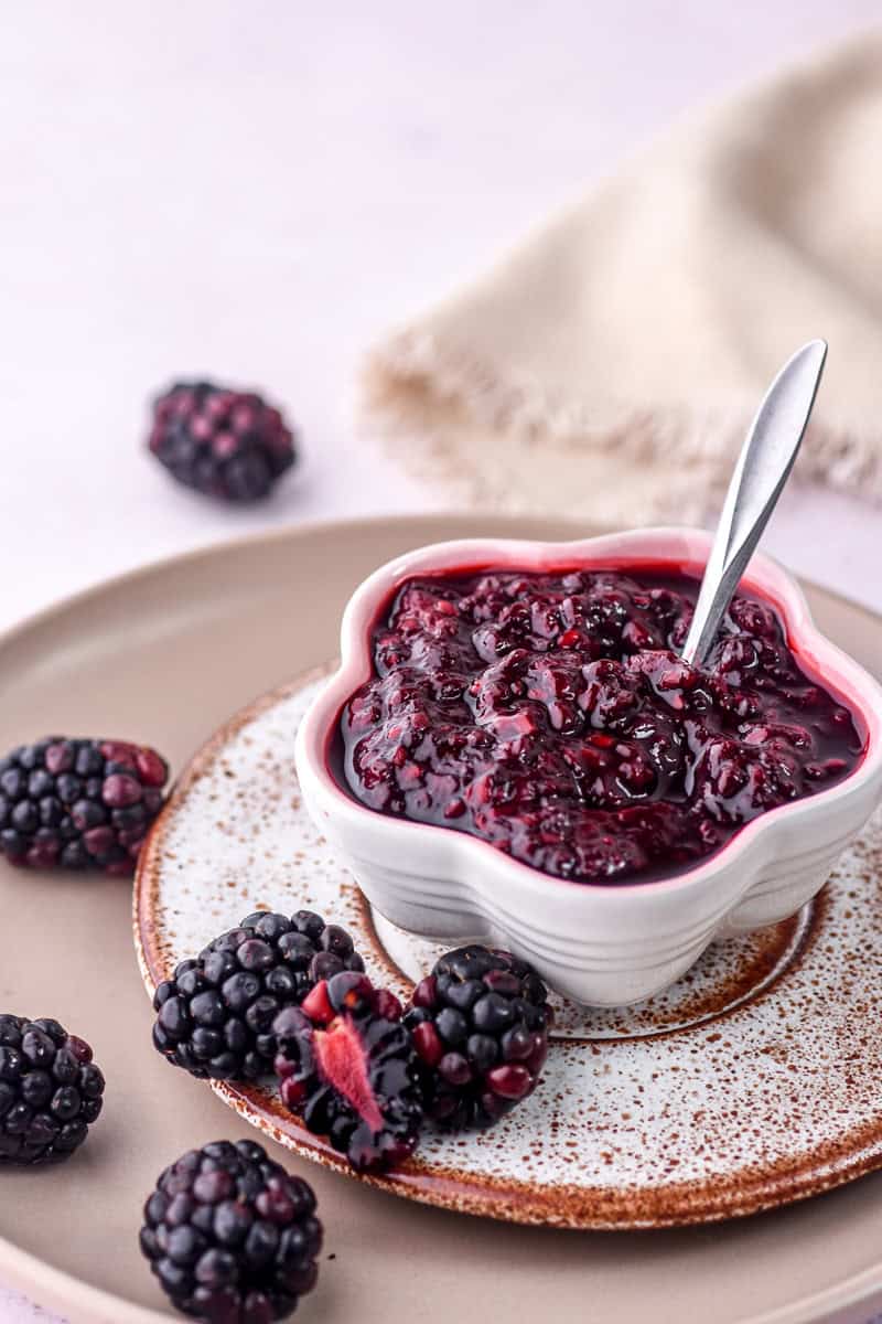 Blackberry Compote shown in a small bowl with a little spoon sticking out of the compote.