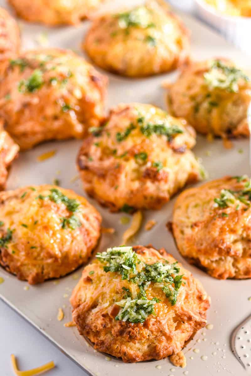 Muffins shown in a muffin tray, you can see their crispy cheesy tops. 