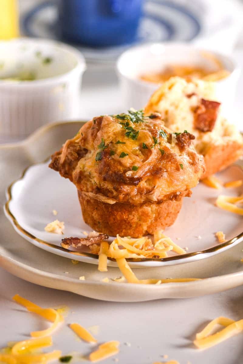 Image showing a single muffin on a stack of plates, there is grated cheese scattered around. 